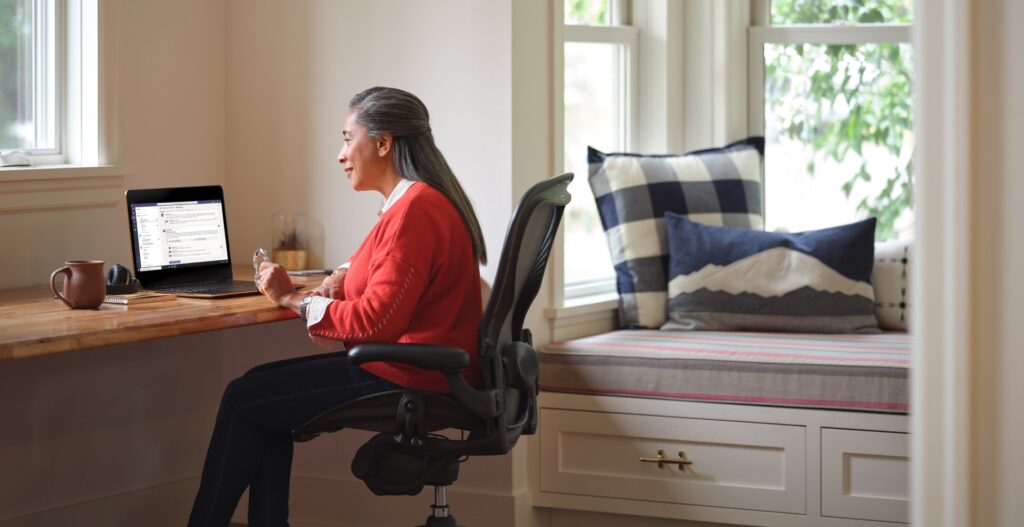 woman sitting at desk with Teams application open on laptop