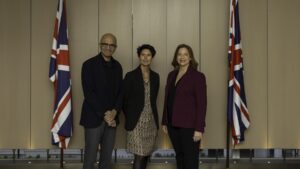 Three people standing in front of two United Kingdom flags. From left to right) Satya Nadella, Chairman and CEO, Microsoft; Cat Little, Chief Operating Officer for the Civil Service and Permanent Secretary to the Cabinet Office; Clare Barclay, CEO, Microsoft UK.