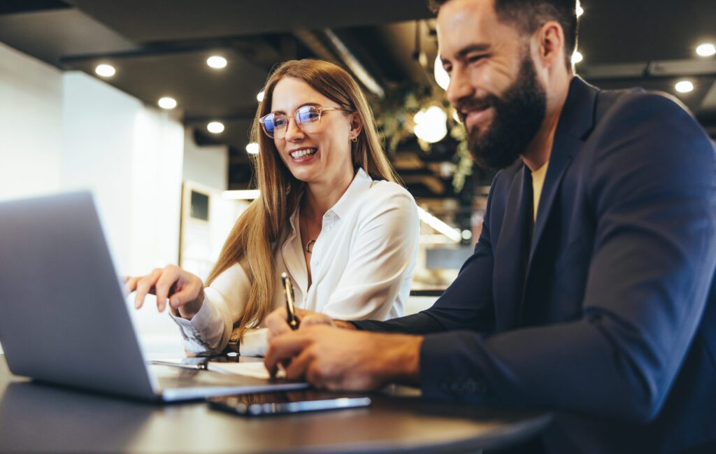 Two people are sitting in front of a computer and smiling.