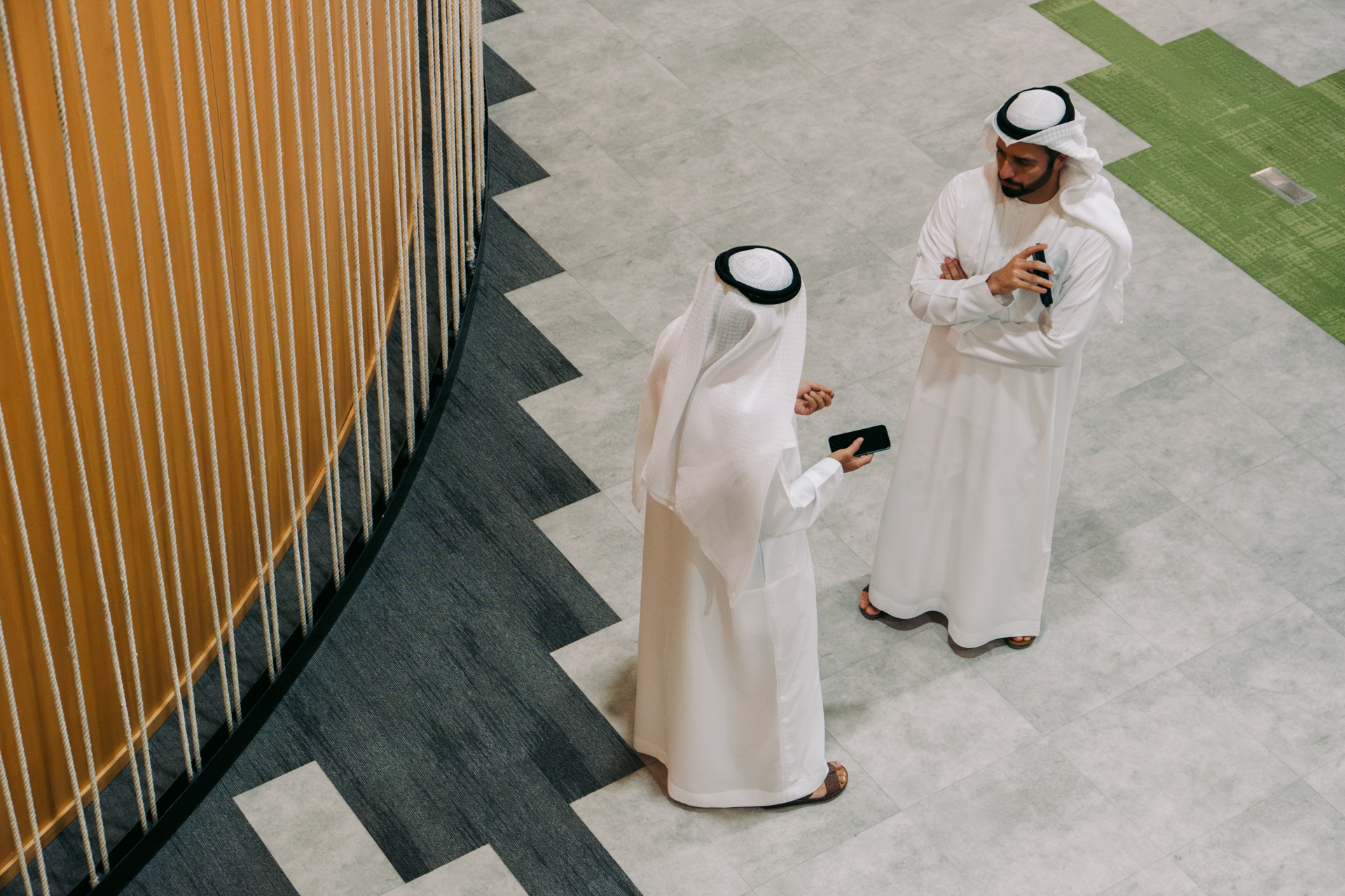 Two men in traditional Emirati clothing talking as seen from above.