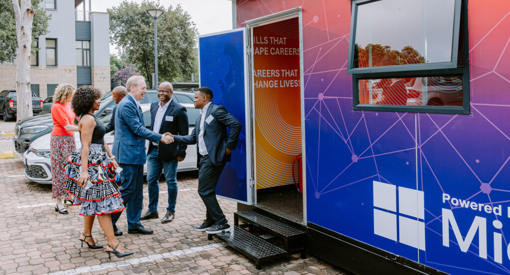 Brad Smith, Vice Chair and President of Microsoft meeting with Deviare Co-Founders and Directors, Lubabalo Dyantyi and Baxolile Mabinya, outside a mobile computer lab.